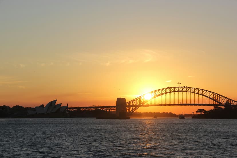 Sydney Opera House and Harbour Bridge at sunrise with golden light reflecting on harbor water